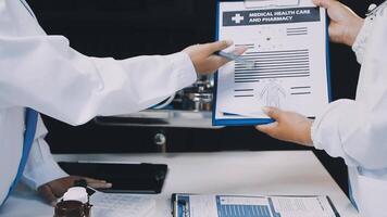 Two doctors are holding a clipboard and looking at a paper video