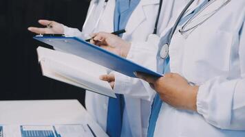 Two doctors are holding a clipboard and writing on it video