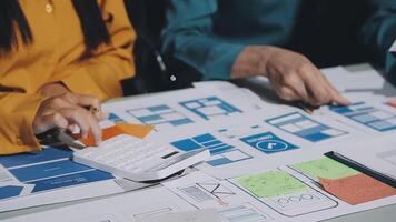 Two people working on a project with papers and a calculator video