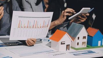 People looking at a house model with a paper and a calculator video