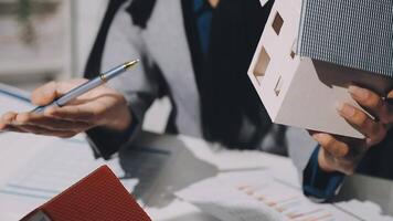 A person holding a house model and a pen video