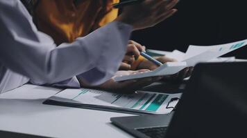 Two people sitting at a table with papers and a laptop video
