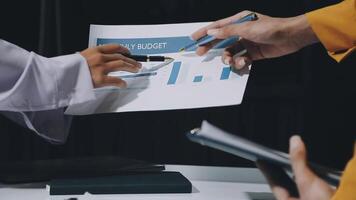 Business people holding papers and pen in front of a table video