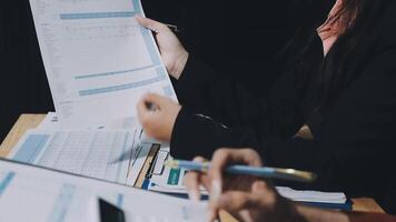 Two people sitting at a table with papers and pens video