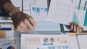 A person is working on a computer with papers and graphs video
