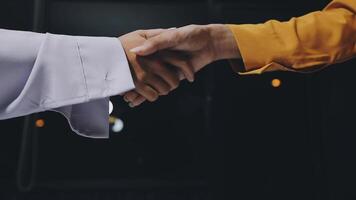 Two people shaking hands in front of a dark background video