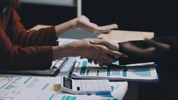 Two people shaking hands over a desk with papers and calculators video