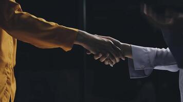 Two people shaking hands in a dark room video