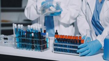 Two people in lab coats and gloves are working on a table video
