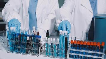 Two people in lab coats and gloves are working on a table video