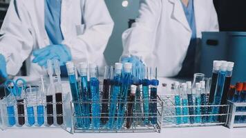 Two people in lab coats are working on a table with test tubes video