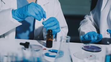 Two people in lab coats and gloves are working on a vial video