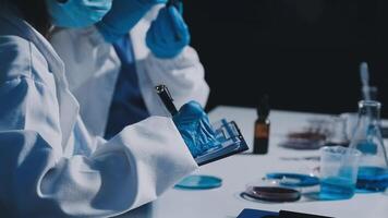 Two people in lab coats and gloves working on something video
