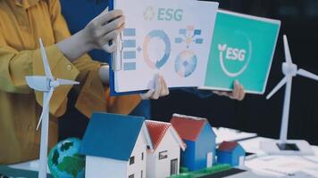 Two people holding up a paper with a house and wind turbines video