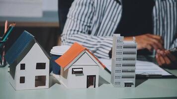 A person is sitting at a desk with a house model video