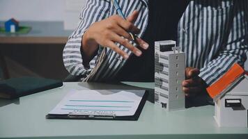 A person is holding a pen and paper while looking at a model of a house video