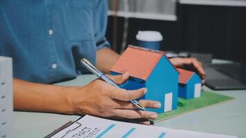 Man writing on paper with house model video
