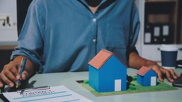 A man signing a contract with a house model video