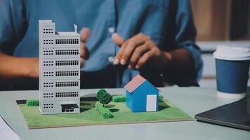 A man is working on a laptop with a model of a building video
