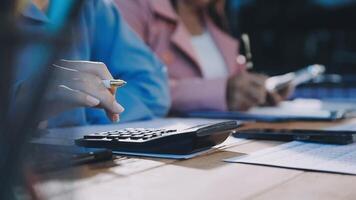 Two people sitting at a table with a calculator and pen video