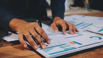 un negocio de la persona manos son en un cuaderno con gráficos y documentos video