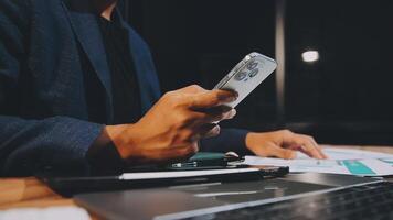 A man in a suit holding a cell phone while sitting at a desk video