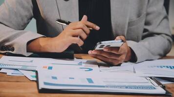 A man in a suit is using his phone while sitting at a desk video