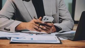 A man in a suit is using his phone while sitting at a desk video