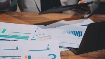 Businessman using laptop and papers with graphs video