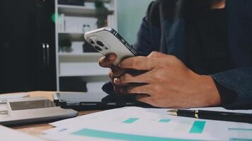 A person in a suit is using a cell phone while sitting at a desk video