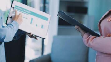 Two people in business attire holding a clipboard video