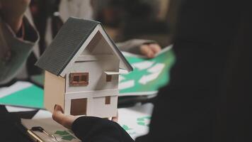 A person holding a model house with a paper house on it video