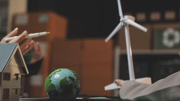 A woman is working on a project with a wind turbine and a green globe video
