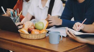 A group of people sitting at a table with a laptop and a basket of fruit video