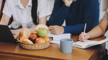 A group of people sitting at a table with a laptop and a basket of fruit video