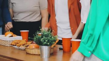 A group of people standing around a table with food video