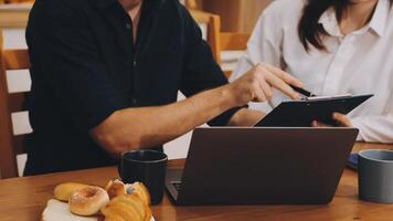 A man and woman are working on a laptop while sitting at a table video