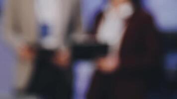 Blurred image of business people standing in front of a screen video