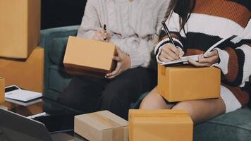 A couple sitting on a couch with boxes and a laptop video