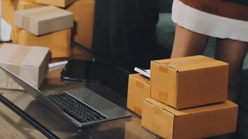 A woman is standing on a table with boxes and a laptop video