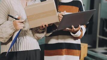 Two women holding boxes and a laptop video