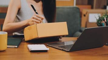 A woman is working on her laptop while holding a box video