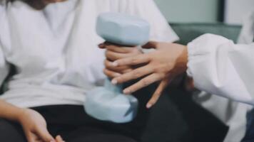 A woman is holding a dumbbell while sitting on a couch video