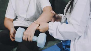 A woman is holding a dumbbell while a man is sitting on a couch video