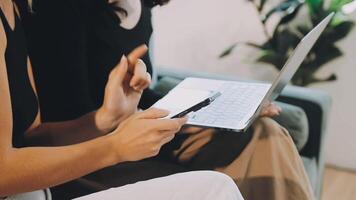 Two women sitting on a couch with their laptops video