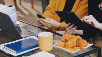 Two people sitting at a table with food and laptops video