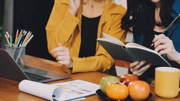 Two women sitting at a table with a laptop and a notebook video