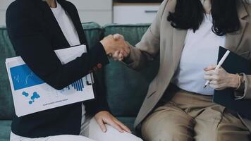 Two business people shaking hands while sitting on a couch video