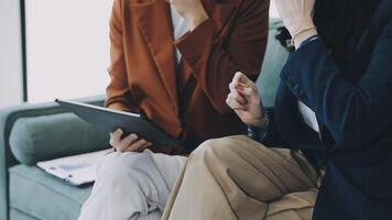 Two businesswomen sitting on a couch with a tablet video