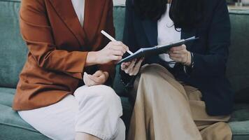 Two women sitting on a couch with a pen and paper video